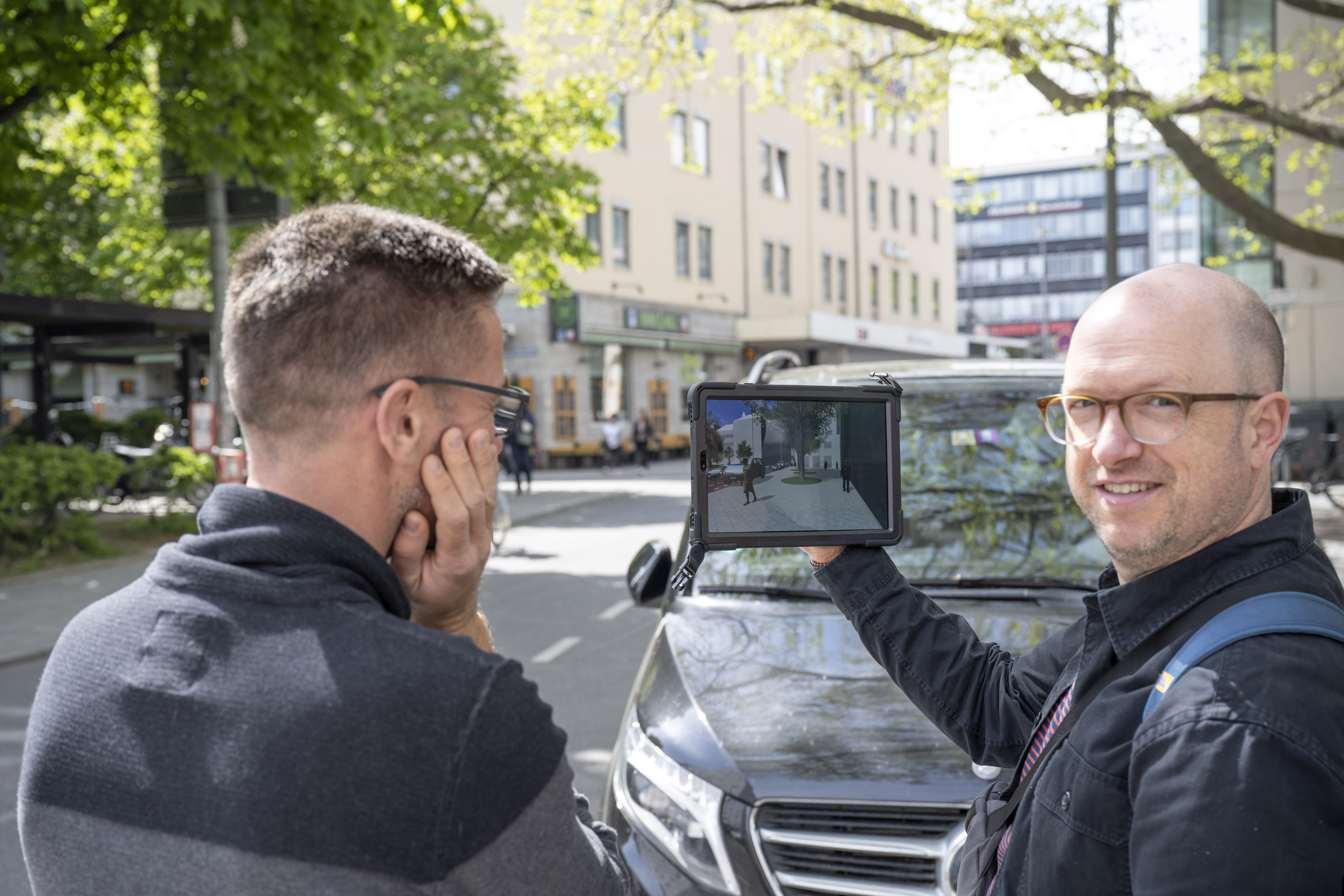 Foto von zwei Personen, die ein Tablet mit der 3D Szene des Freiraumquartierskonzept Innenstadt Fokusraum 