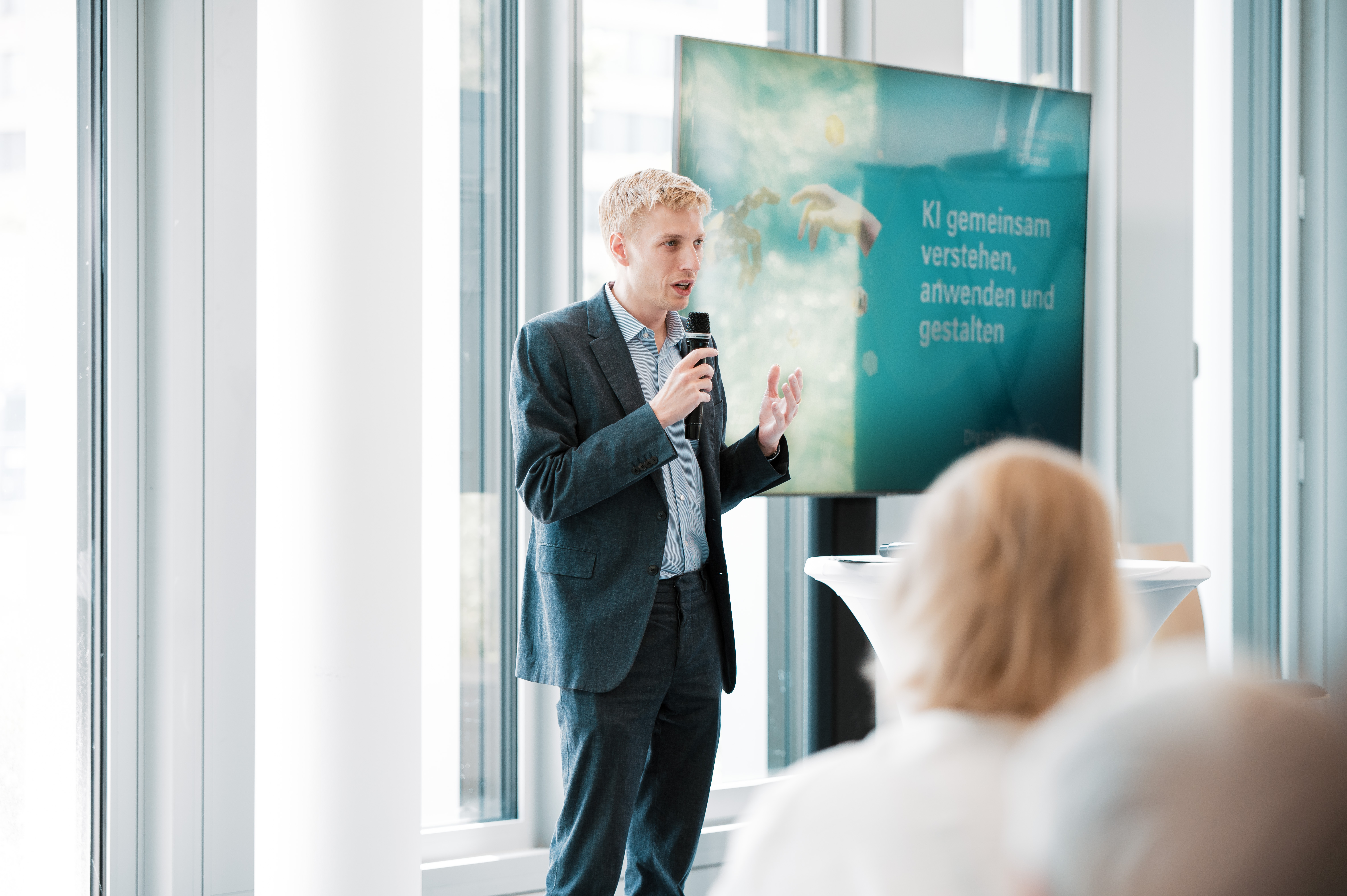 Im Vordergrund ist der zweite Bürgermeister Dominik Krause von hinten zu sehen, der auf das Publikum schaut.