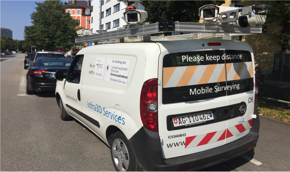 Ein Befahrungsfahrzeug der Firma iNovitas mit Kameraaufbau. Auf der Heckscheibe steht 'Please keep distance Mobile Mapping', auf der Seite des Autos 'infra3D Services' und ein Aufkleber mit dem Text 'im Auftrag der Landeshauptstadt München Kommunalreferat GeodatenService'.